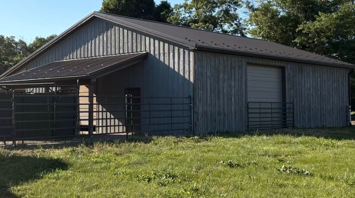 Gray stained pole barn with dark metal roof
