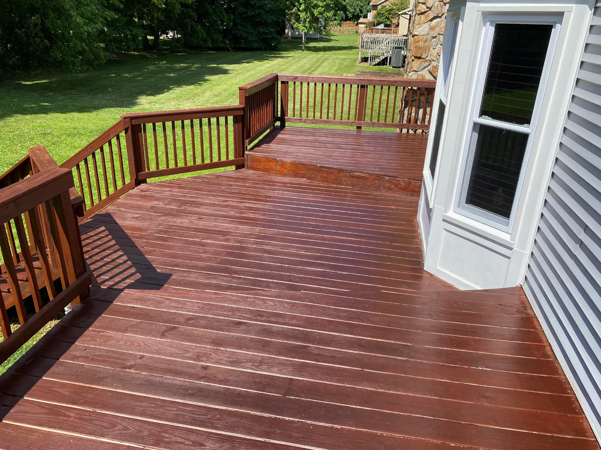 Freshly stained multi-level deck with rich walnut rails and floorboards